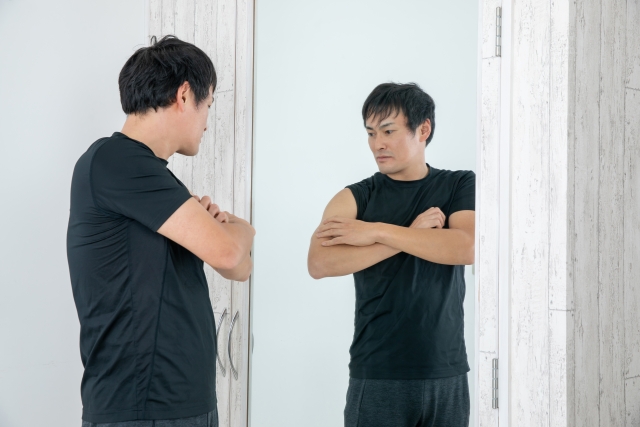 鏡の前で筋肉をチェックする男性